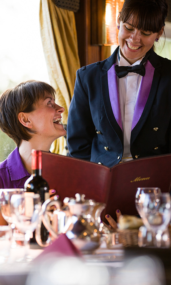 A guest discussing the menu with a crew member aboard the Lord of the Glens cruise ship